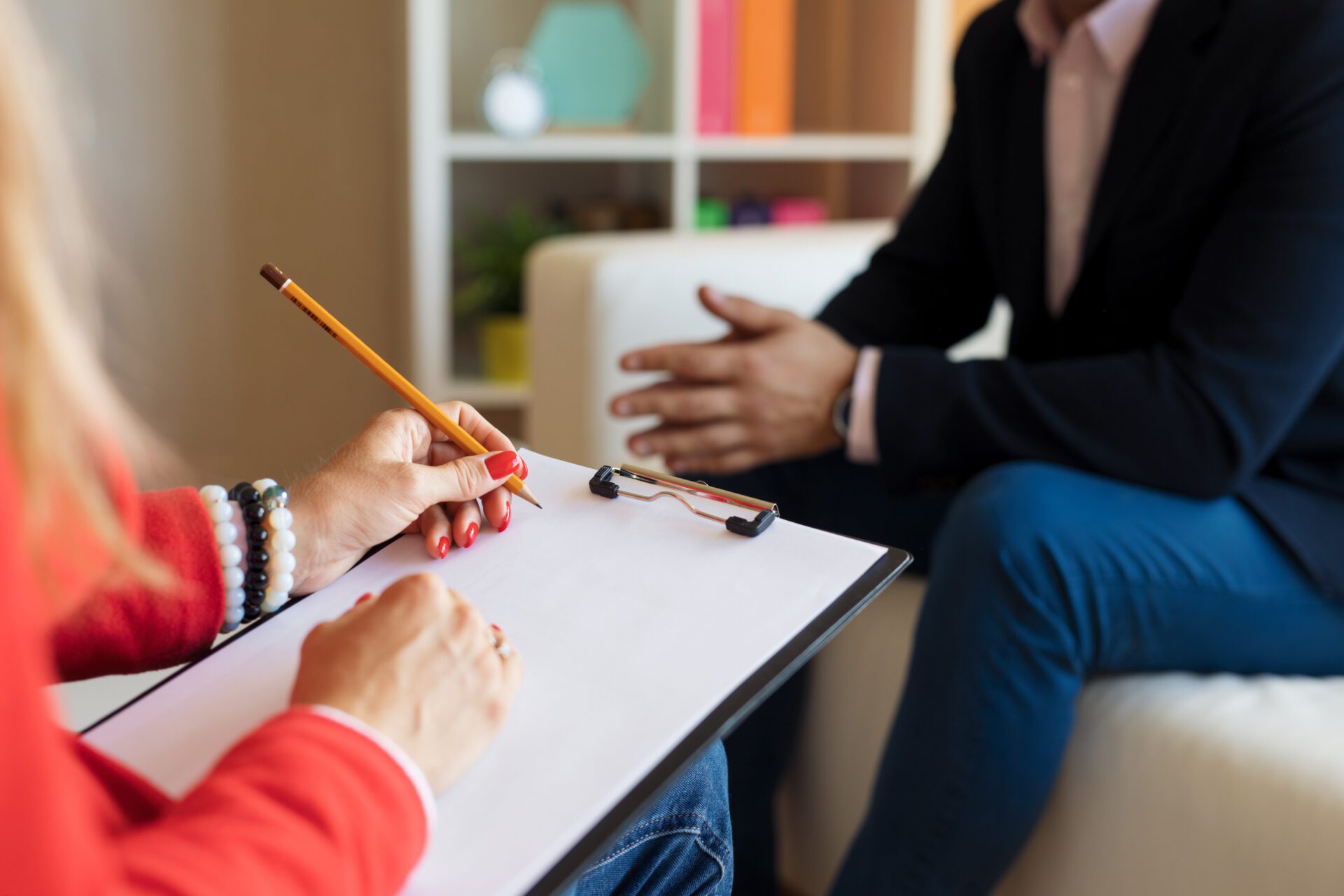 Man at therapy session Counselor making notes while young woman crying during therapy session at office