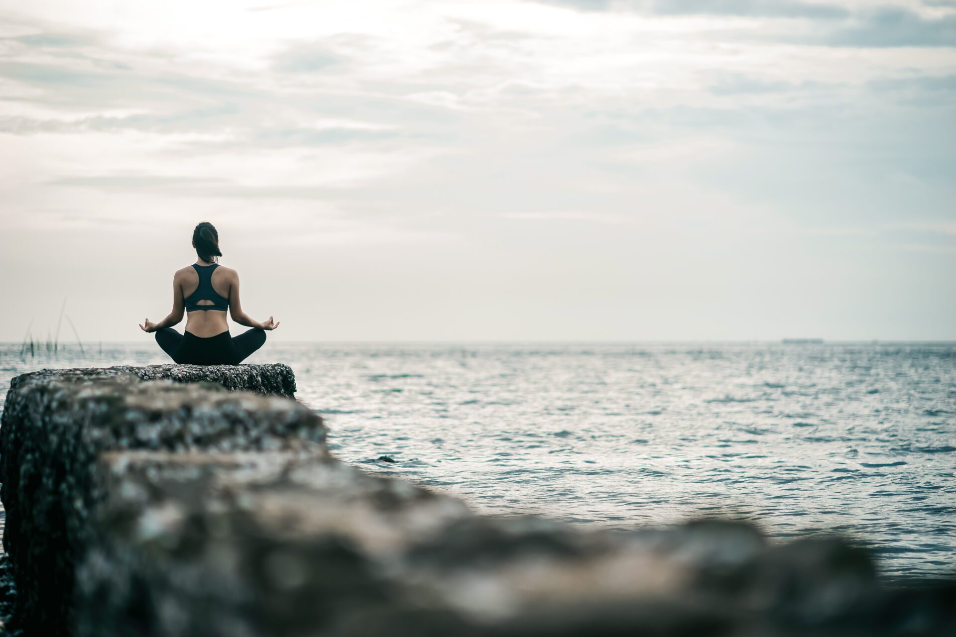 Young Asian woman practicing yoga exercise at quiet rock pier with sea background. Sport and recreation in city rush. Young Asian woman practicing yoga exercise at quiet rock pier with sea background. Sport and recreation in city rush.